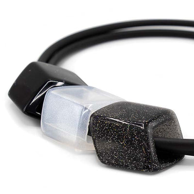 Detail van ketting met rubber met drie cubes in zwart en wit 