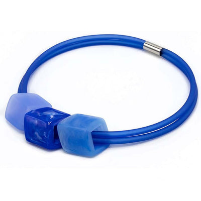 Ketting met 3 Cubes in lichtblauw, kobaltblauw en marmerblauw aan blauwe rubber ketting met zilverkleurige sluiting, zijaanzicht.