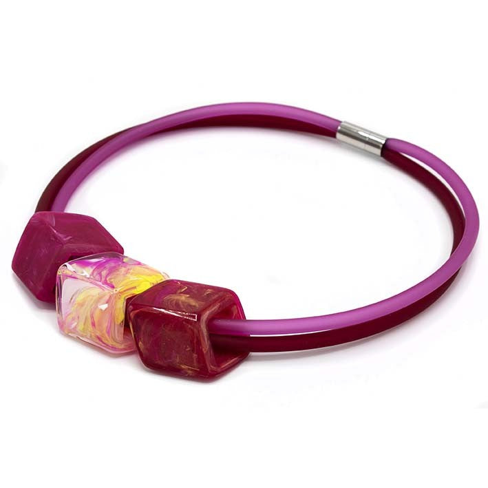 Ketting met 3 Cubes in felle tinten roze, geel en rood aan roze rubber ketting met zilverkleurige sluiting, zijaanzicht.