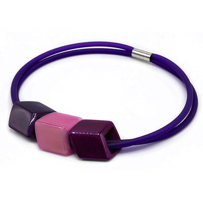 Ketting met 3 Cubes in paarstinten (paars, roze, magenta) aan paarse rubber ketting met zilverkleurige sluiting, zijaanzicht.